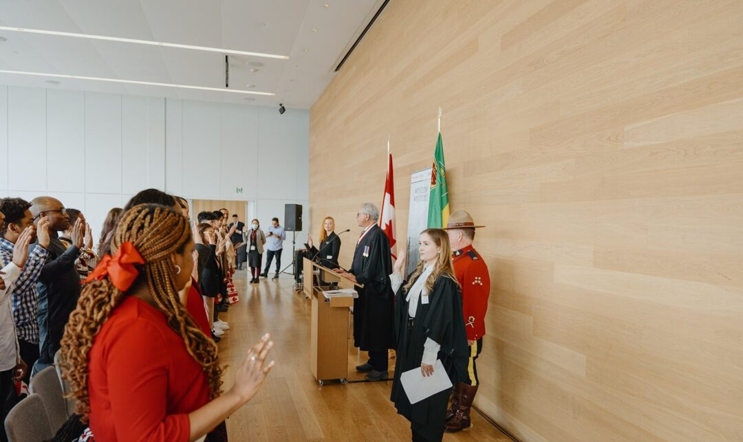People holding up their hands to take an oath of citizenship.